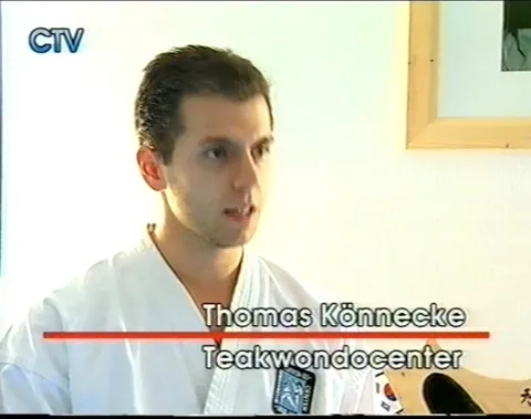 Screenshot Chiemgau TV vom 19. März 2002: Thomas Könnecke im Dobok im Interview, Namensbanner „Thomas Könnecke, Taekwondocenter"