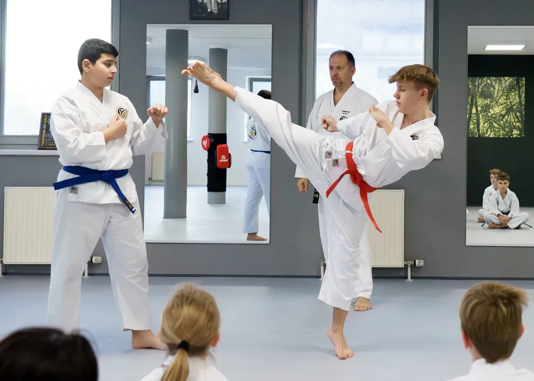 Jugendliche beim Taekwon-Do-Training in Traunreut – kontrollierte Partnertechnik mit einem Trainer als Aufsicht