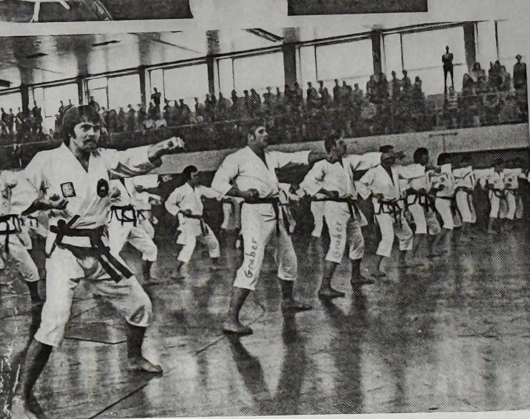 Großlehrgang in einer Sporthalle: zahlreiche Teilnehmer in weißen Anzügen üben Fußtechniken, im Hintergrund Zuschauer auf der Tribüne, Leipheim 1975