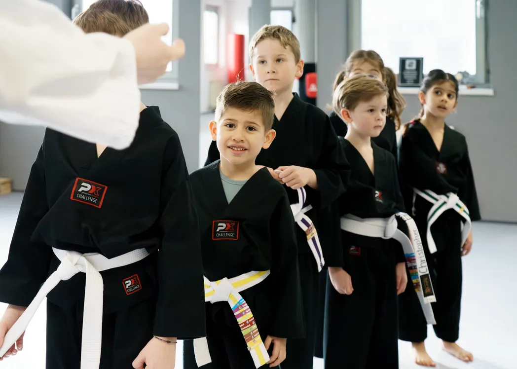 Panda-Kids-Gruppe steht aufmerksam in einer Reihe, während der Trainer eine Übung anleitet