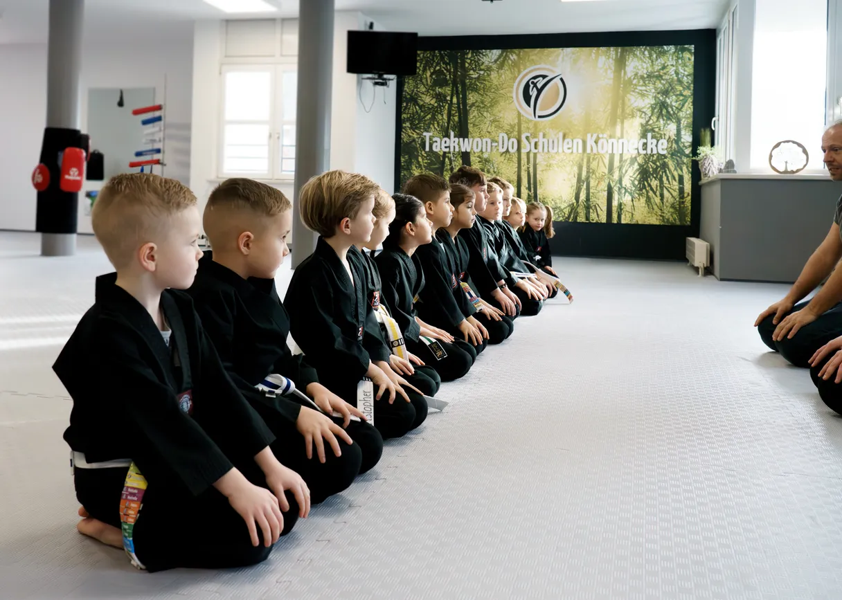 Panda-Kids-Training – Vorschulkinder sitzen aufgereiht vor dem Trainer