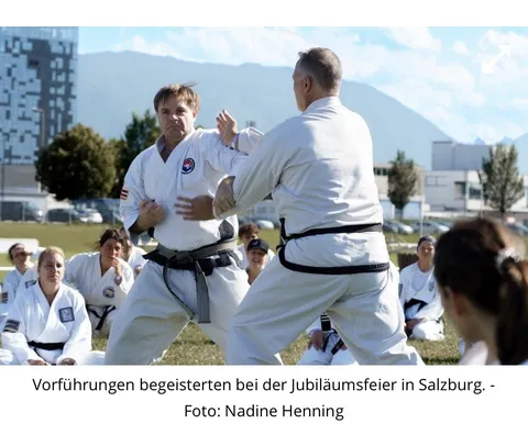 Zeitungsfoto aus dem PNP-Artikel: Zwei Taekwondo-Trainierende in weißen Anzügen bei einer Vorführung im Freien, im Hintergrund sitzende Teilnehmer und die Salzburger Berge