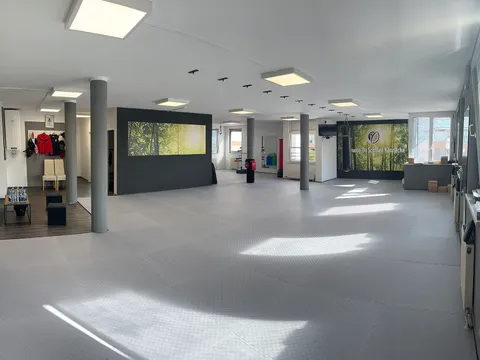 Trainingshalle der Taekwon-Do Schule Könnecke in Salzburg mit Kampfsportmatten, Spiegelwand und Boxsack