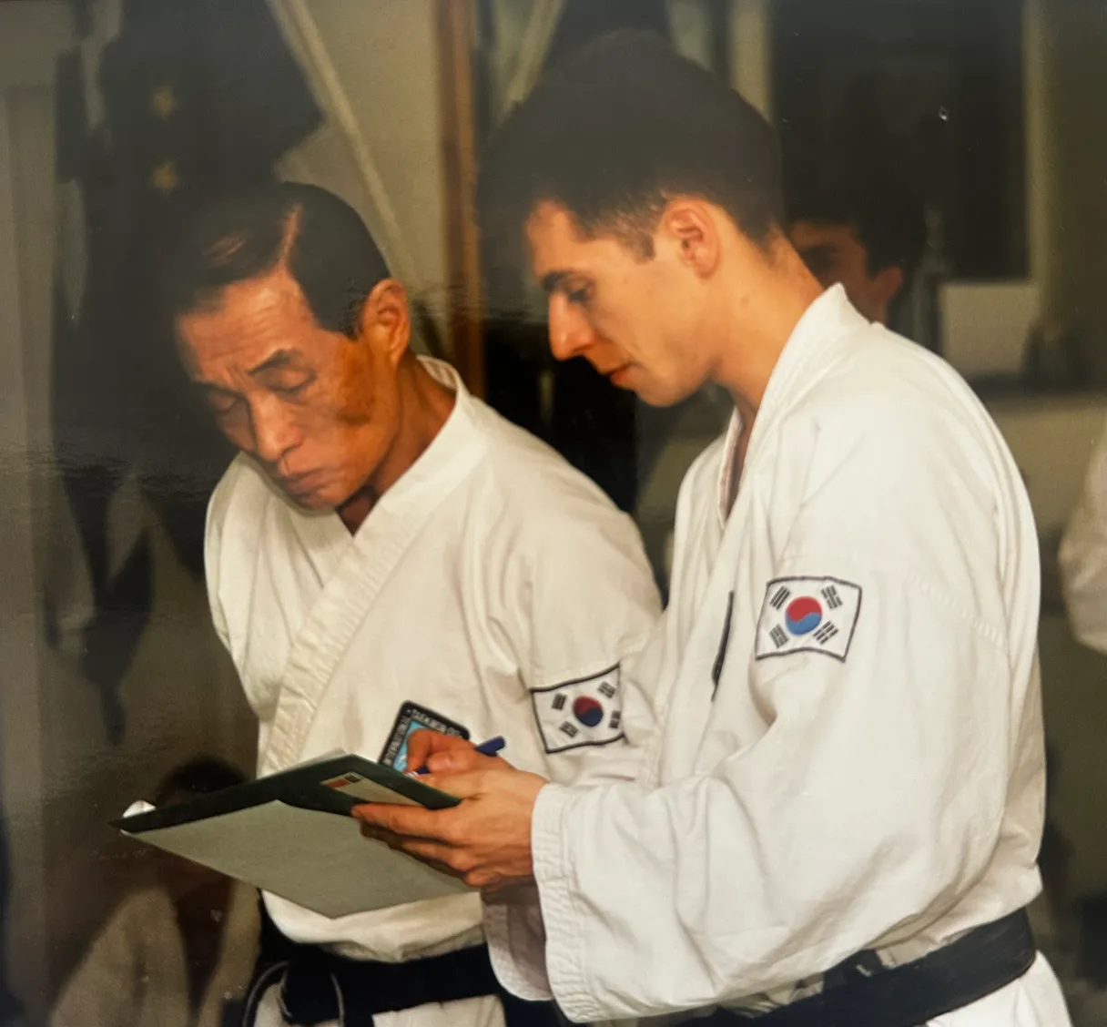 Der junge Thomas Könnecke im Dobok notiert sich etwas neben Großmeister Kwon Jae-Hwa, Ottobrunn 1997