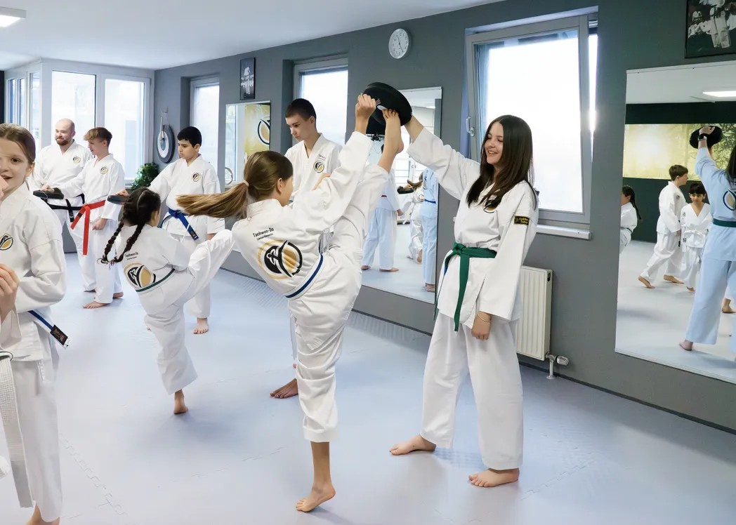Tiger-Kids-Training bei Taekwon-Do Übersee – Pratzentraining zwischen zwei Kindern mit lachendem Partner