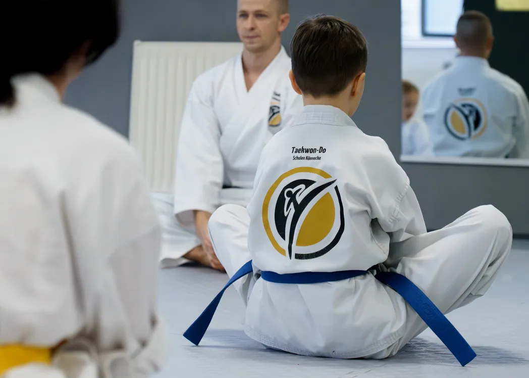 Tiger-Kids-Training bei Taekwon-Do Neuötting – ein Kind sitzt aufmerksam vor dem Trainer, im Hintergrund die Trainingsgruppe